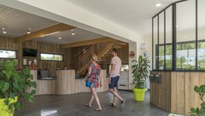 Un área de recepción moderna con un mostrador de madera, una escalera y plantas en macetas.