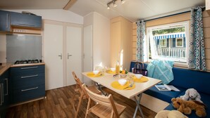 Una cocina compacta con estufa a gas, armarios de madera y un comedor con mesa dispuesta para dos.