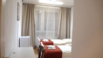 Two single beds with white linens, a desk, and chair await guests in this well-maintained room.