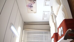A bedroom with a bed, a window with curtains, a wall-mounted air conditioner, and a ceiling light. - Apartment Osterstraße 322 zwei (Hannover)