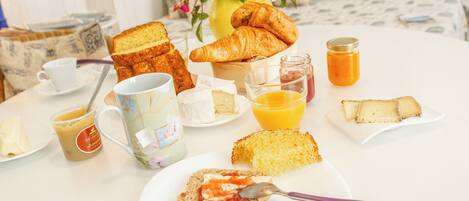 A breakfast table with croissants, toast, jam, butter, and a mug of coffee.