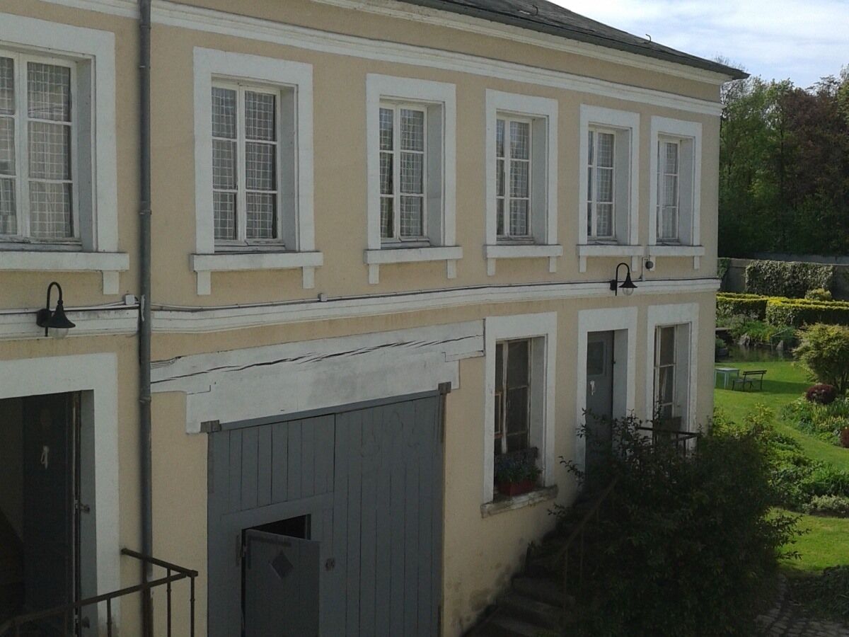 A two-story building with a beige facade, white trim, and multiple windows.