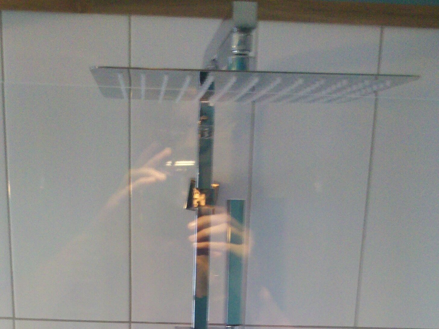 A shower with a glass enclosure and a vertical handle.