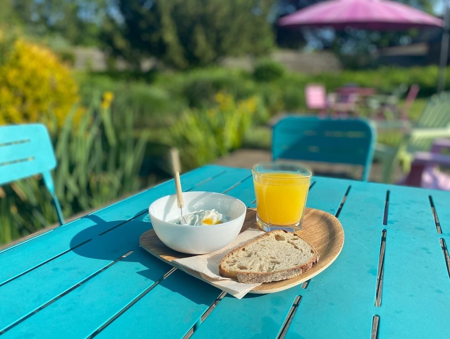 Une table avec un bol de yaourt et un verre de jus d’orange, une tranche de pain et une serviette.