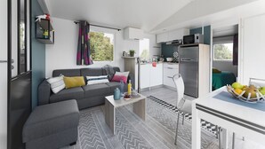 A compact living space with a sofa, coffee table, and a small kitchen area including a refrigerator and microwave.