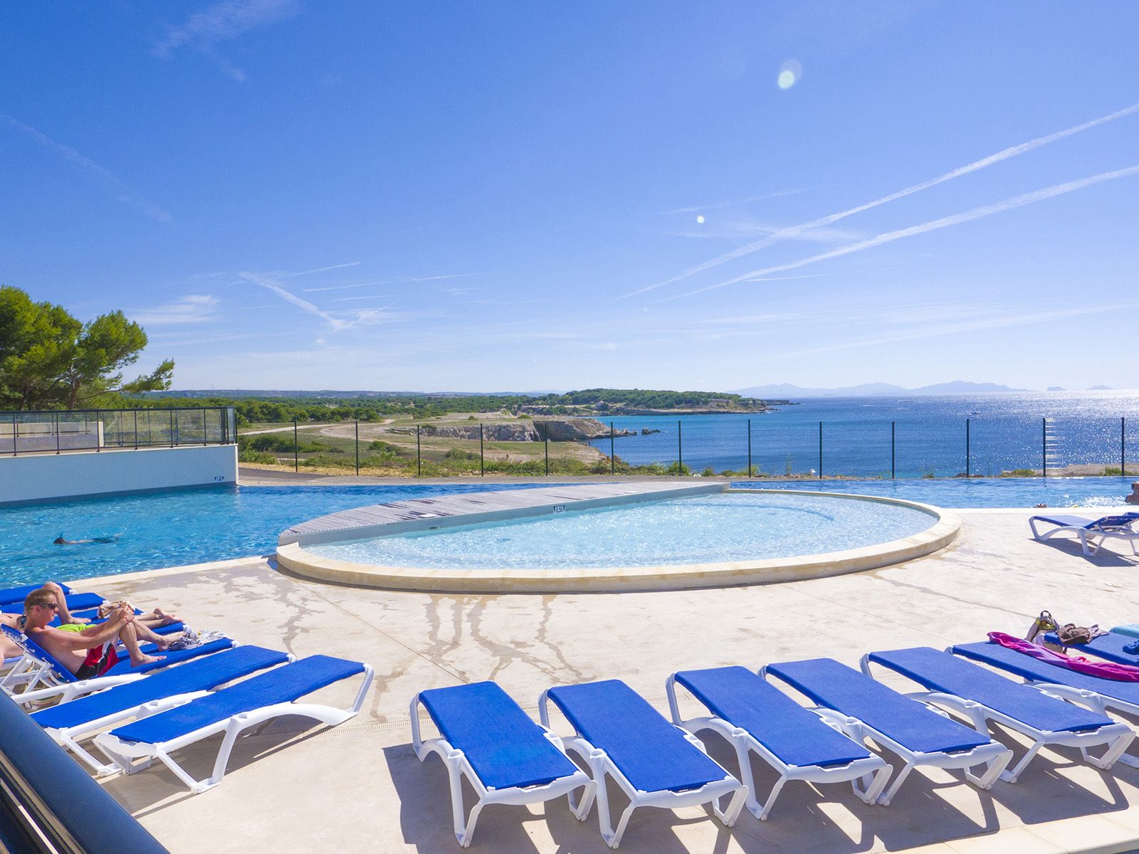 Una piscina al aire libre, sombrillas, sillones reclinables de piscina