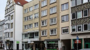 A multi-story building with a mix of architectural styles, including a white facade with a corner tower and a beige building with a patterned facade. - Apartment Osterstraße 324 zwei (Hannover)