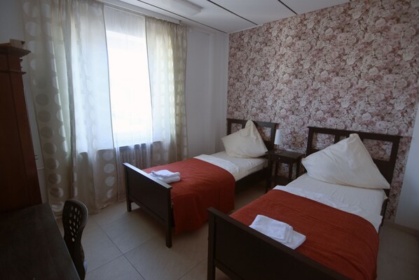 A room with two single beds, a wooden desk, a chair, and a window with sheer curtains. - Apartment Osterstraße 324 zwei (Hannover)