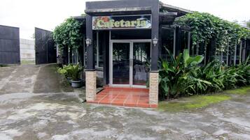 A cafe with a tiled entrance and potted plants.