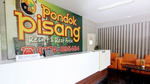 A reception area with a large sign for 'Pondok Pisang Resort & Rest Area', a reception desk, and orange seating. - Hotel Popi Pondok Pisang (Ngaglik)