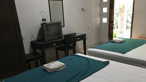 A room with two beds, a desk with a computer and a television, and a window with blinds. - Hotel Popi Pondok Pisang (Ngaglik)