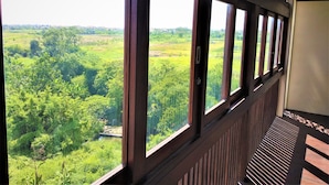 A room with large windows offering a view of a lush green landscape. - Rumah Padi Guest House (Tibubeneng)