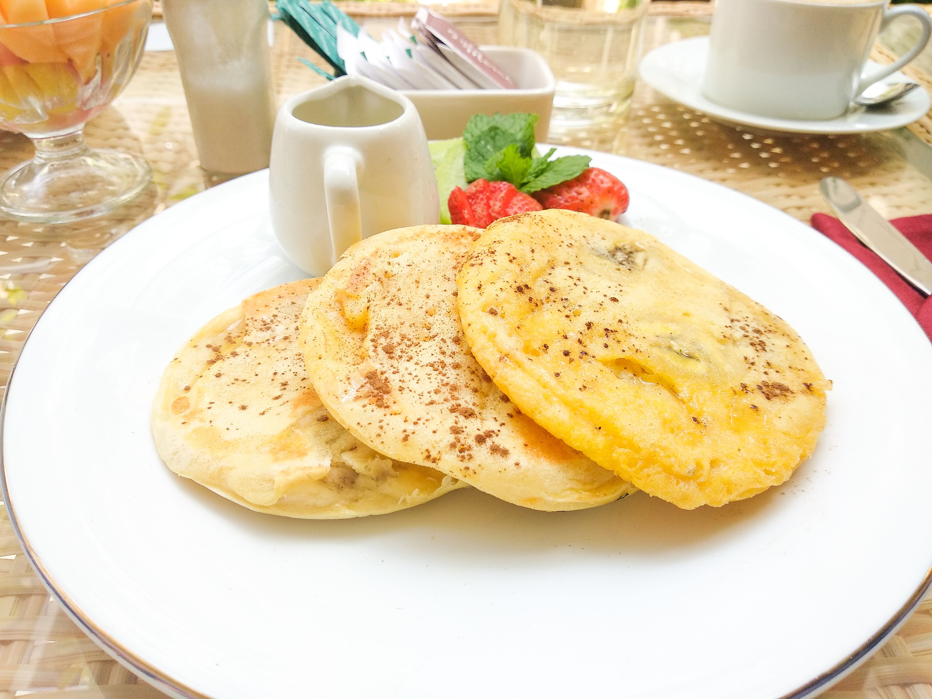 A plate with pancakes, a cup of coffee, and a glass of milk.