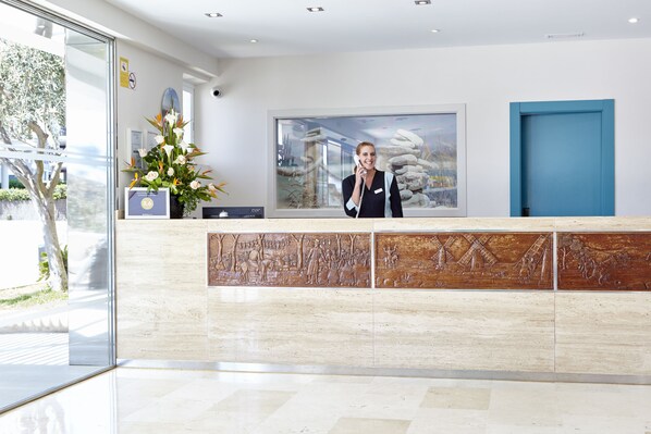 A reception desk with a large window, a blue door, and a wall-mounted phone. - Universal Casa Marquesa (Ses Salines)