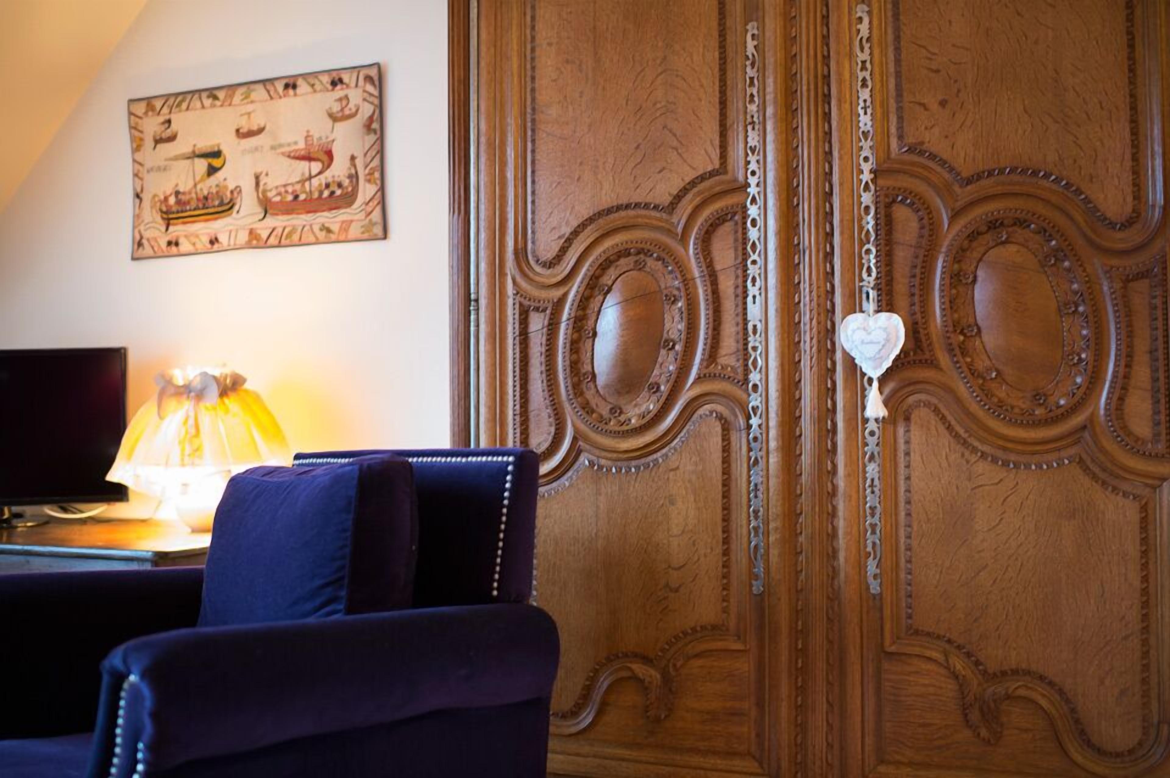 A room with a wooden cabinet, a desk with a lamp, and a chair.