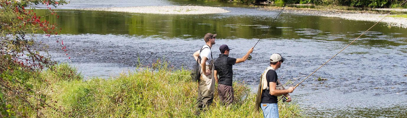 A group of people fishing by a calm river.