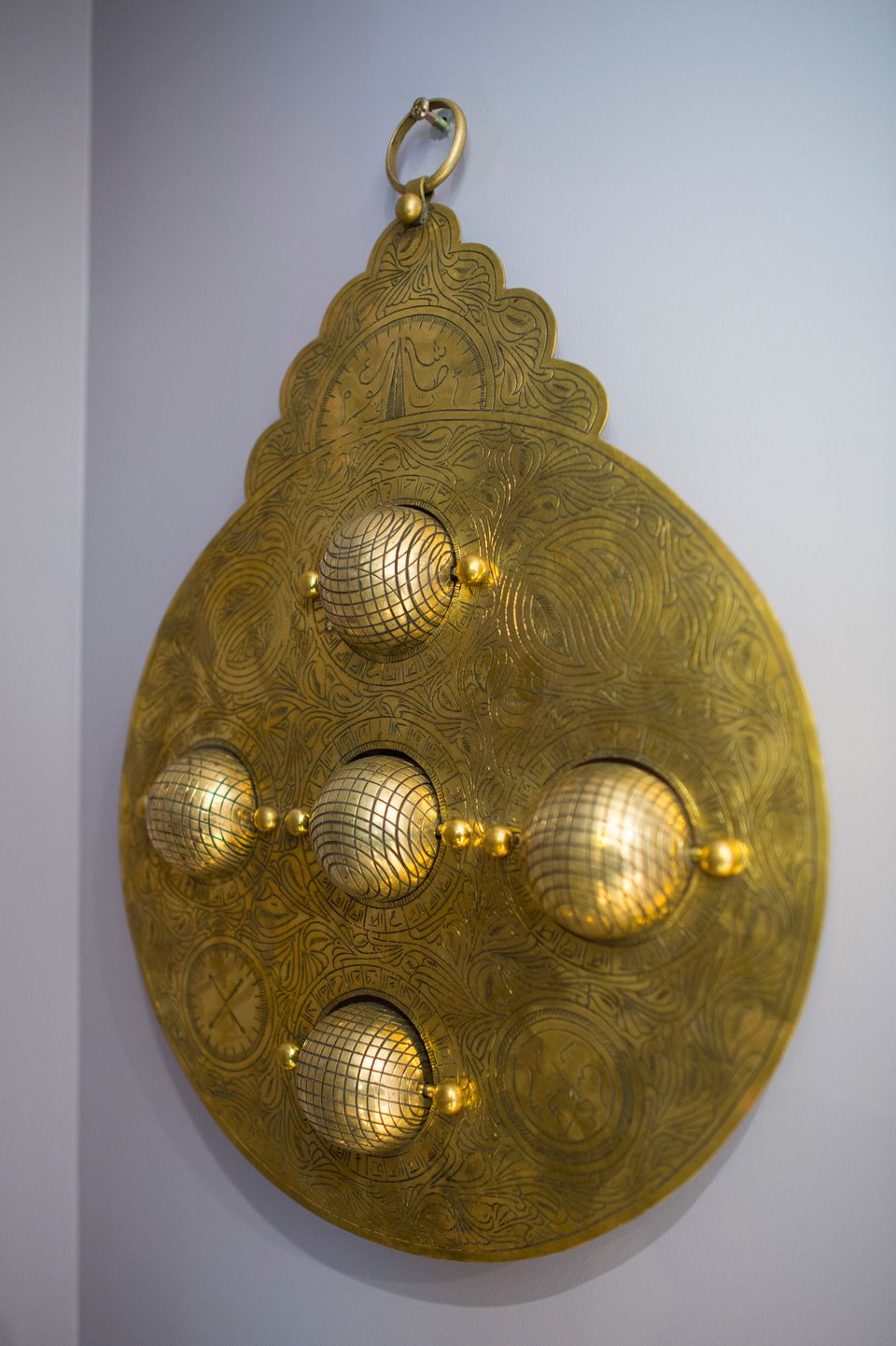 A decorative brass object with intricate patterns and spherical elements.