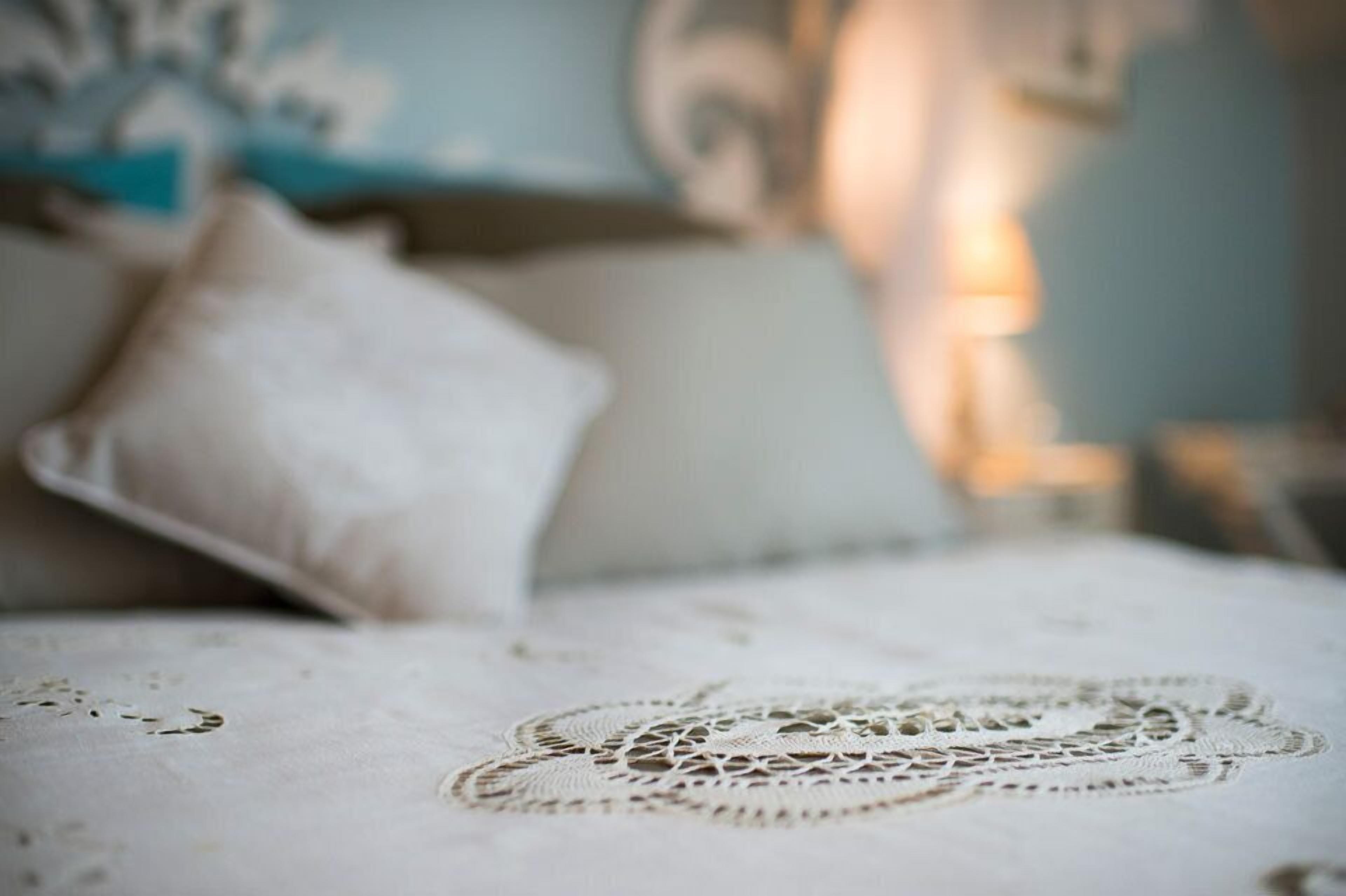 Un lit avec un chemin de table en dentelle et un oreiller.
