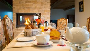Uma mesa de café da manhã com lareira, um bule e diversos itens para o café.