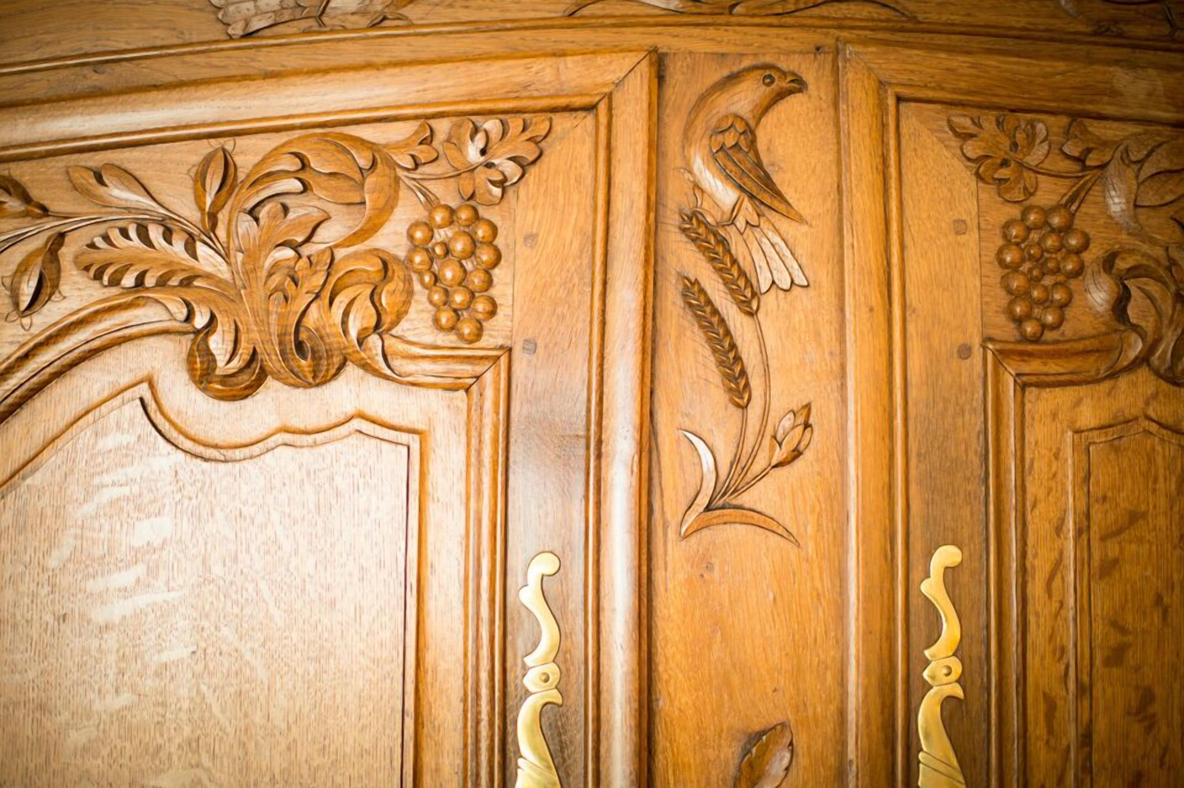 Un panel de madera con elaboradas tallas de hojas, uvas y un pájaro.