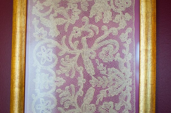 Primer plano de un cortinaje de encaje con estampado floral, enmarcado por un borde dorado.