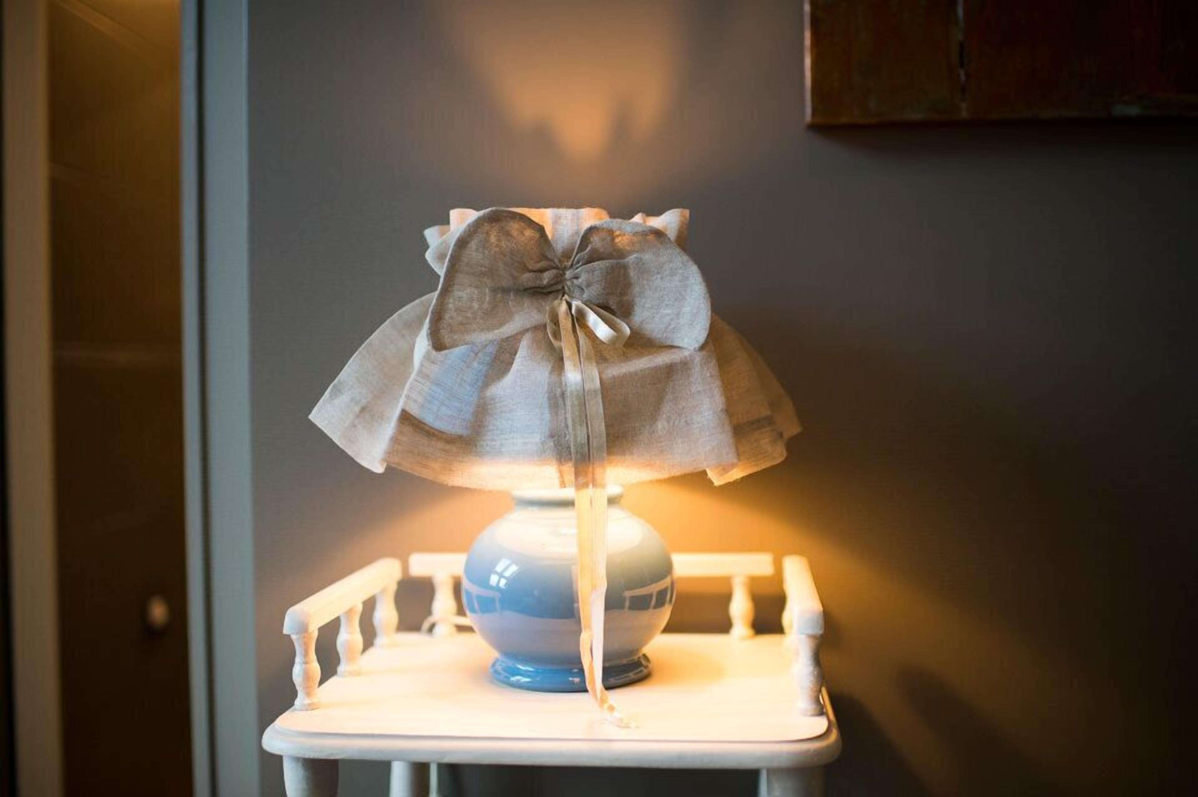 A lamp with a bow on a white chair in a room.