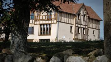 Een huis met twee verdiepingen, een schuin dak, een schotelantenne en een stenen muur op de voorgrond.