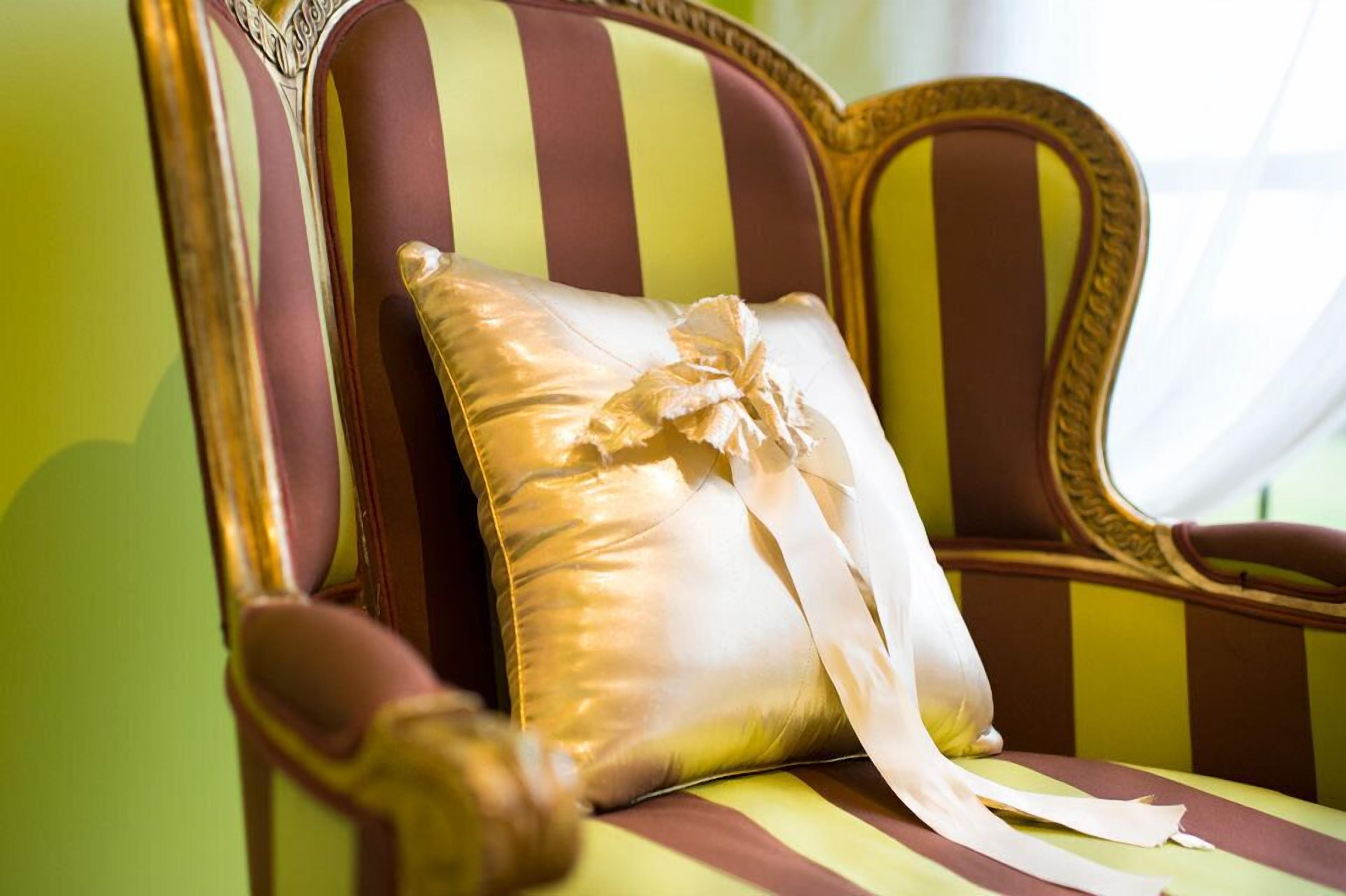 A chair with a striped upholstery and a decorative pillow.