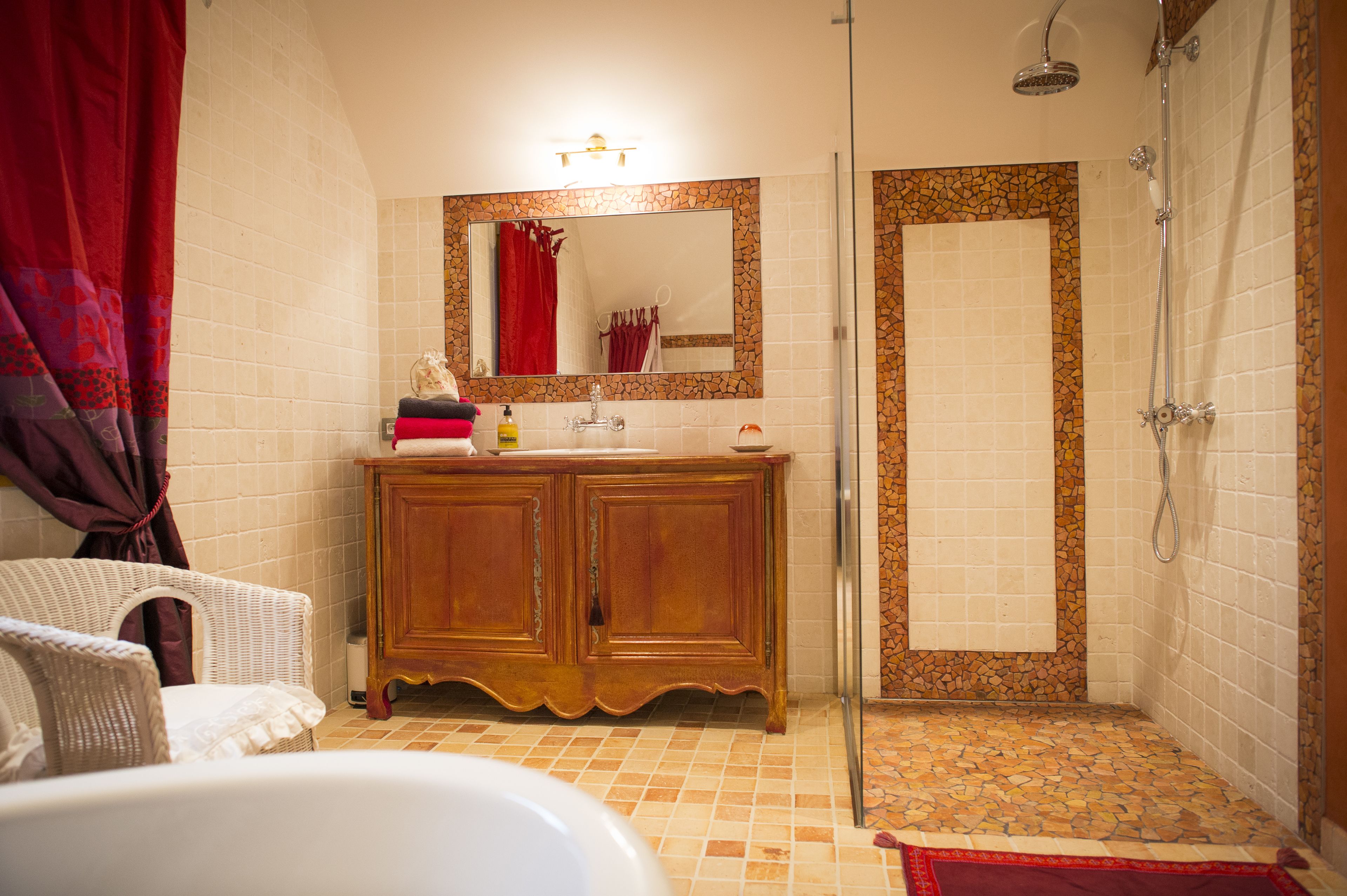 Un baño con tocador de madera, un espejo grande, ducha y una alfombra de baño roja.