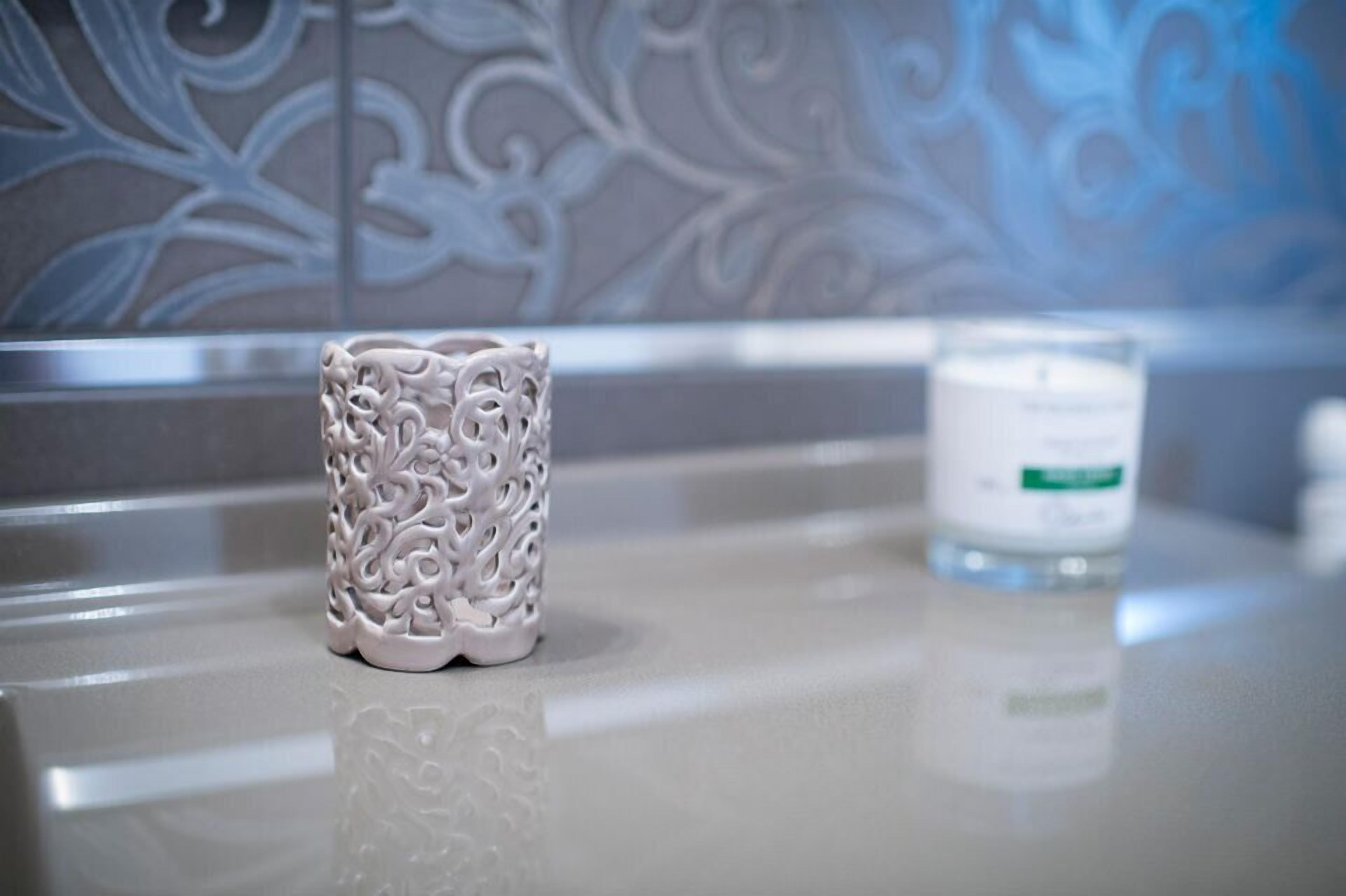 A bathroom with a decorative white vase and a white candle on a countertop.
