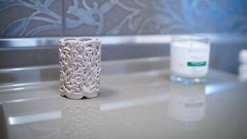 A bathroom with a decorative white vase and a white candle on a countertop.