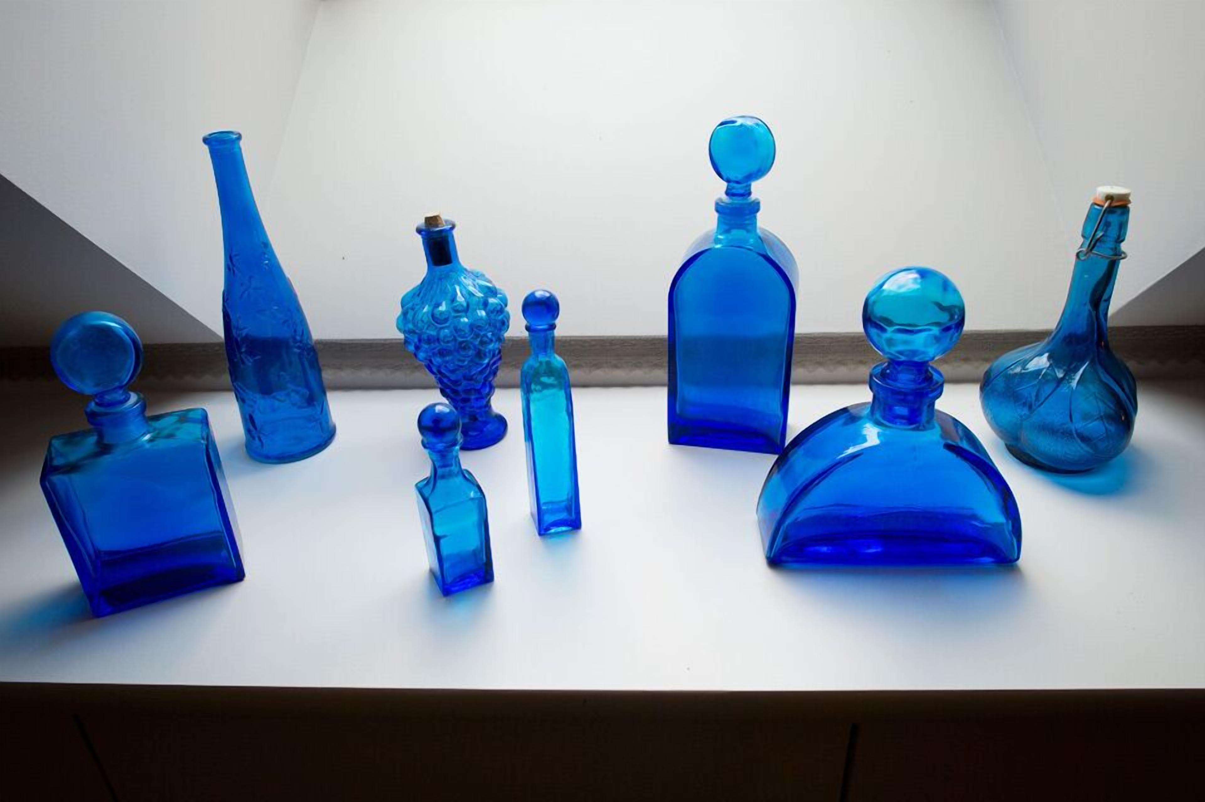 Un conjunto de botellas de vidrio azul sobre una superficie blanca.