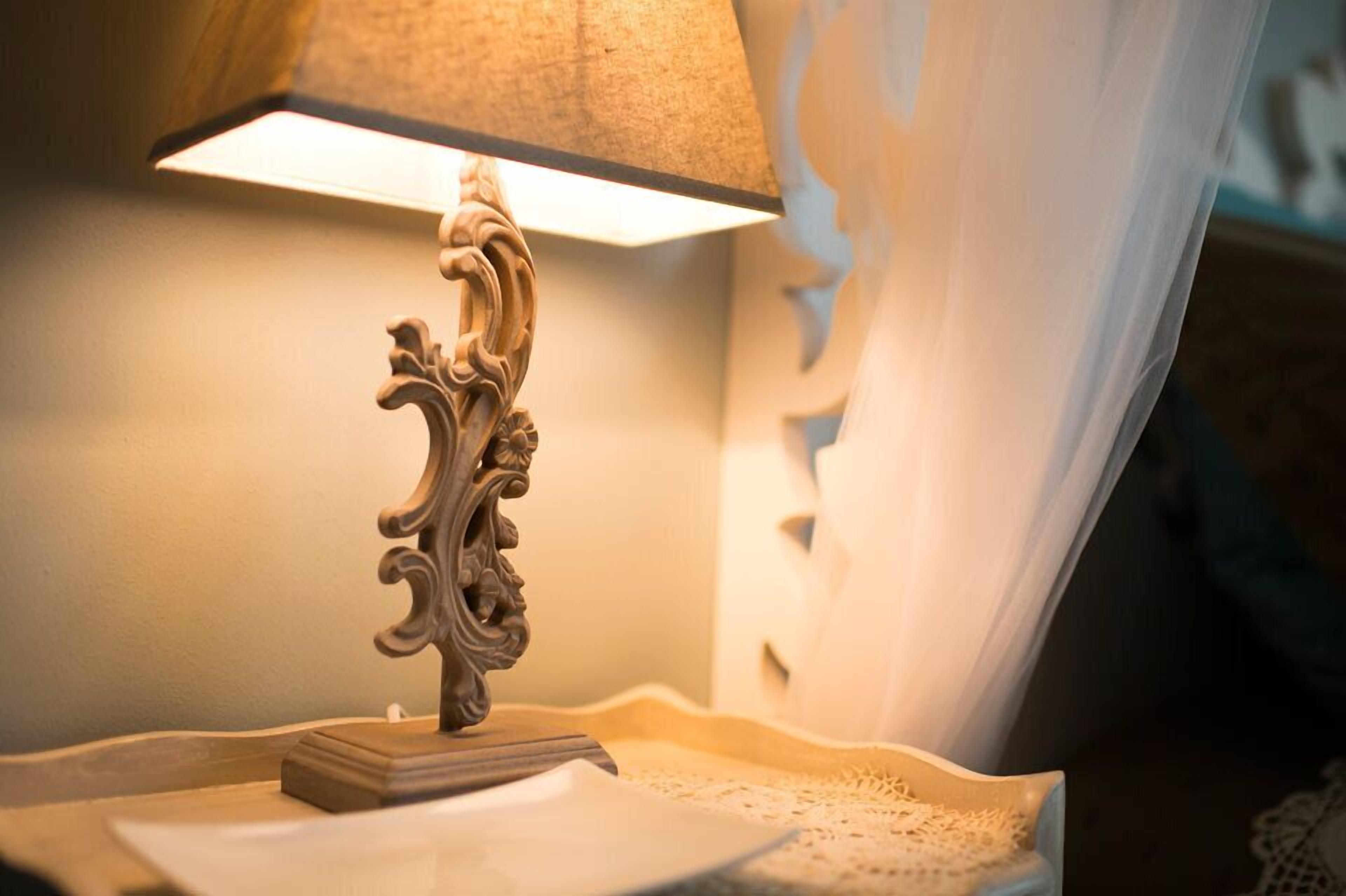 A table lamp with an ornate base on a table with a lace doily.