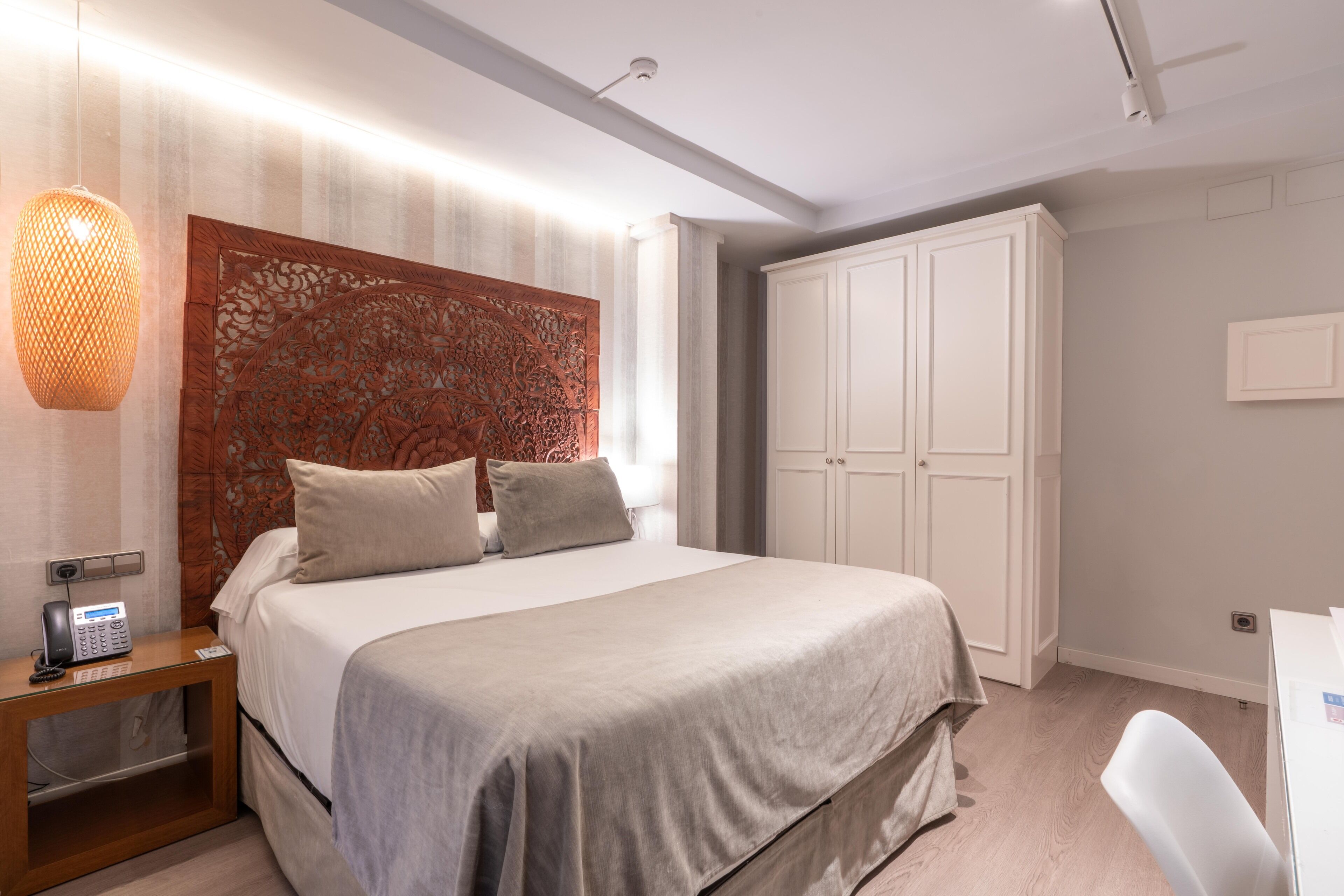 A neatly arranged bedroom with a bed, bedside table, and a wardrobe.