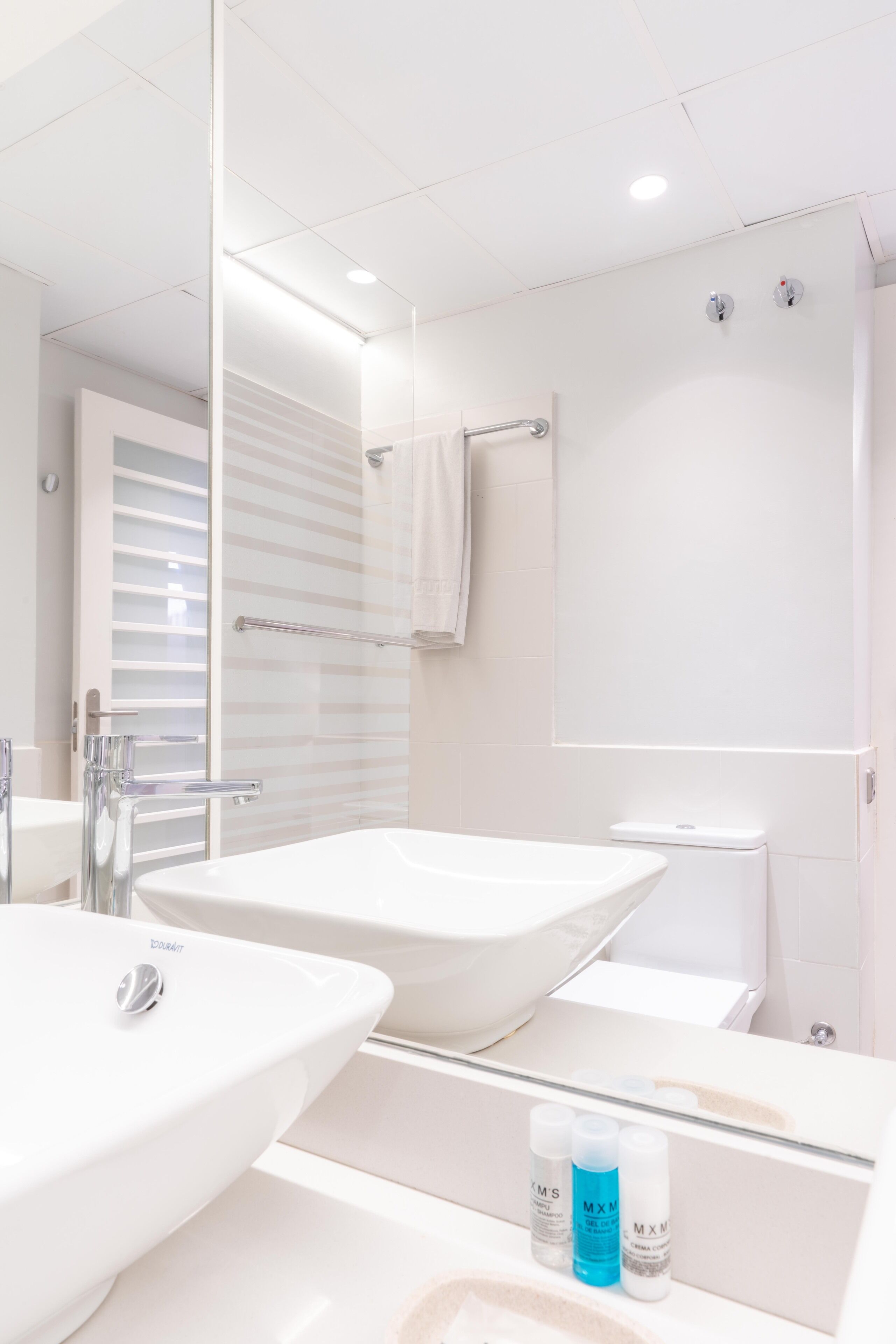 Een moderne badkamer met een grote spiegel, twee wasbakken en een douchecabine.