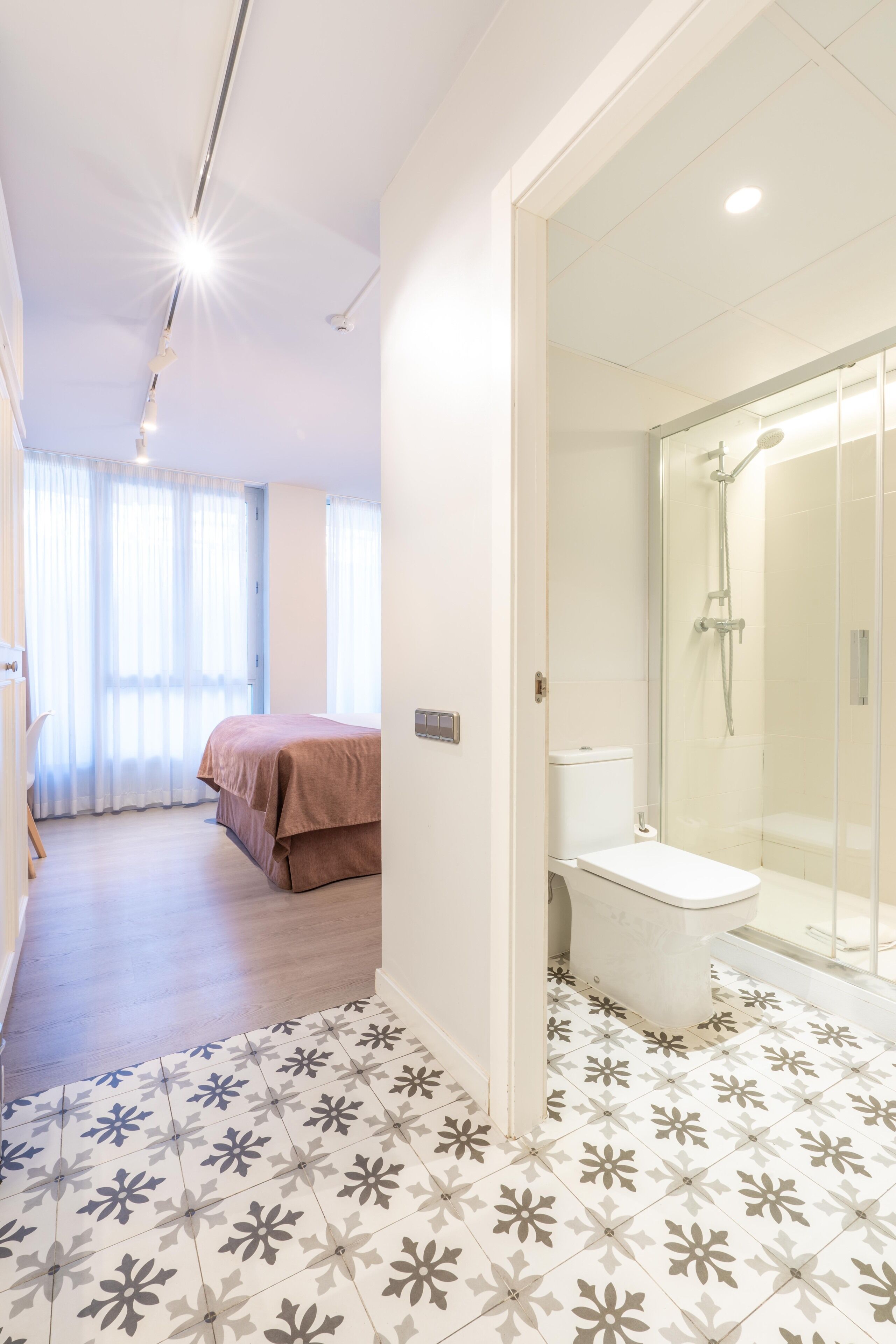 A hotel room with a shower, toilet, and bed.