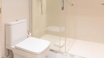Een badkamer met toilet, douchecabine en vloertegels met een patroon.