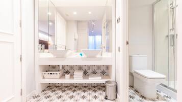 A bathroom with a double sink, a toilet, and a shower.