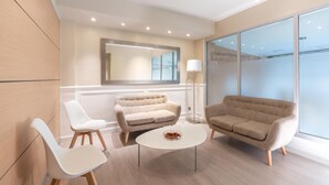 A modern room with a sofa, two chairs, a coffee table, and a large window. - Serennia Fira Gran Vía Exclusive Rooms (L'Hospitalet de Llobregat)