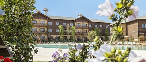 Um hotel com várias varandas, piscina e vegetação exuberante.