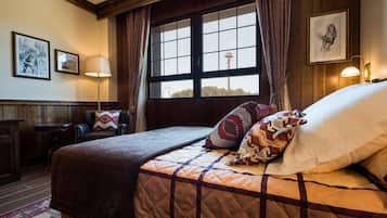 A hotel room with a large bed, a window with a view of a tower, a lamp, and a framed picture on the wall.