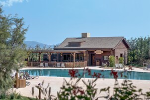 Una cabaña con piscina, zona de estar al aire libre y montañas al fondo.
