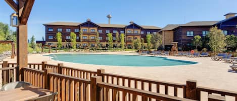 A resort with a pool, outdoor seating, and a building with multiple balconies.