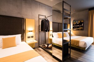 Une chambre d’hôtel avec deux lits, un miroir, un porte-manteau et une œuvre d’art accrochée au mur.