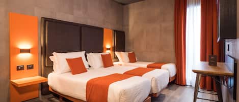 A hotel room with two beds, a small table, and a nightstand.