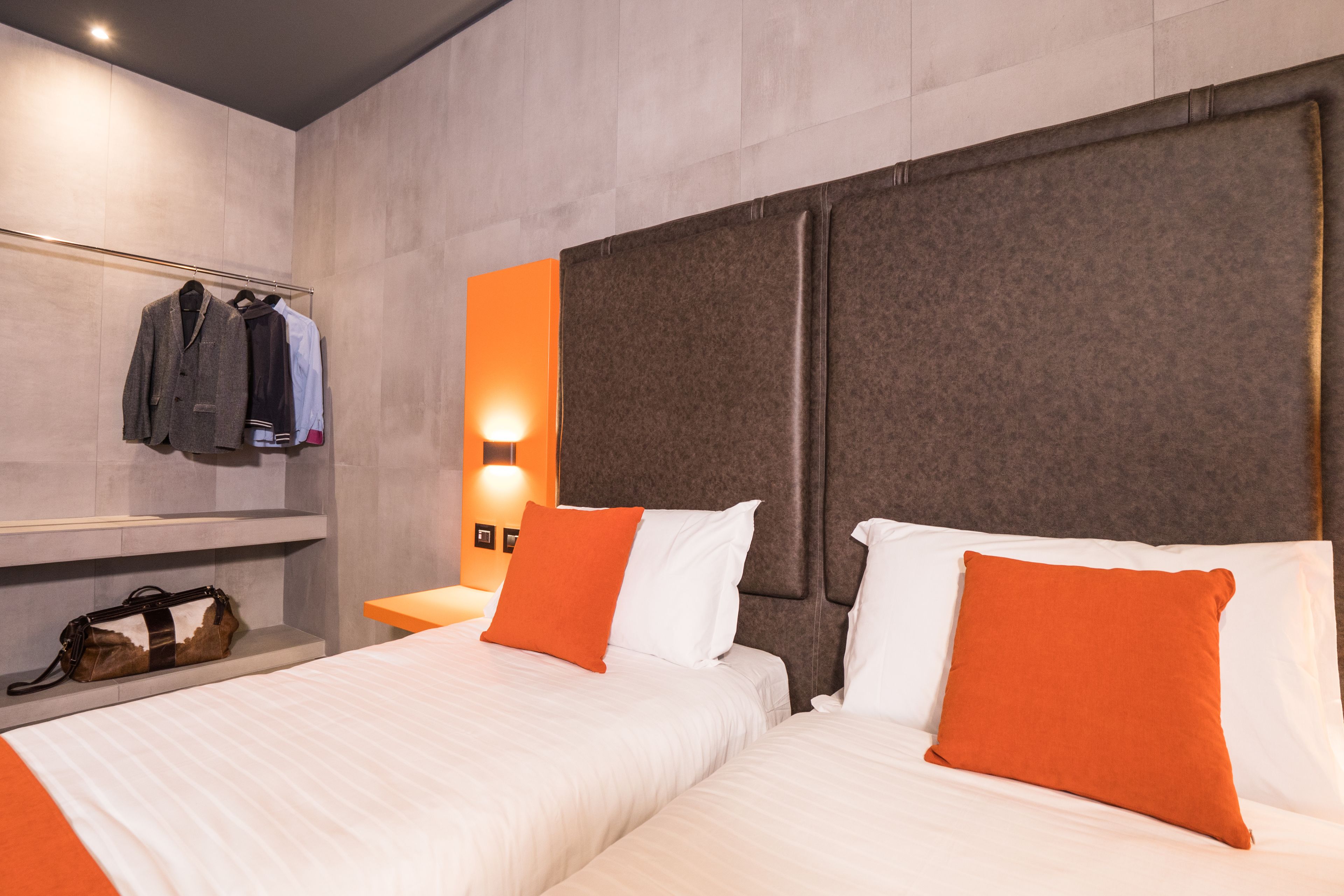 A hotel room with two beds, a wardrobe, and a nightstand.