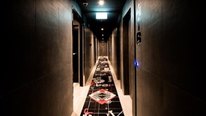 A hallway with a patterned floor, dark walls, and a ceiling light. - J24 Hotel Milano (Milan)