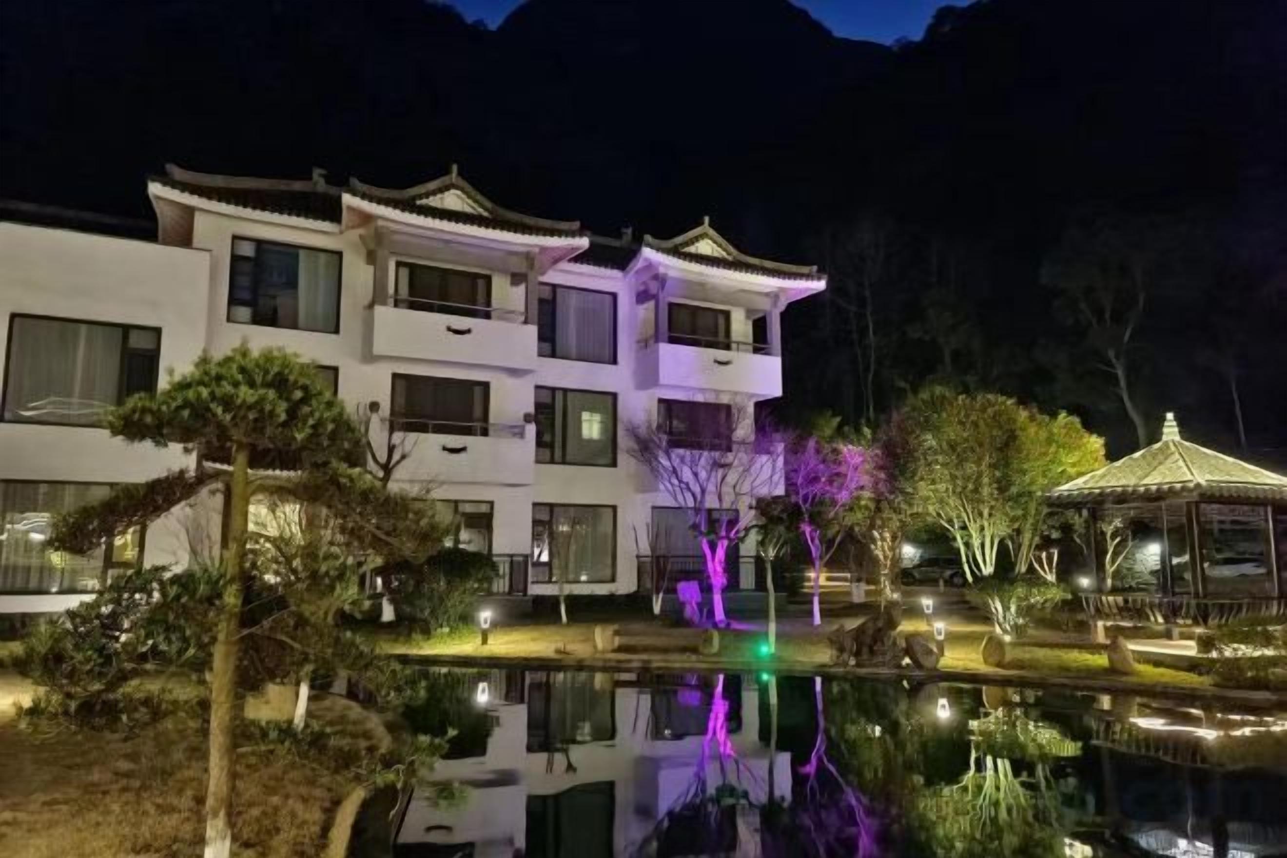 Un edificio de varios pisos con balcones, una fuente reflectante y un pabellón.