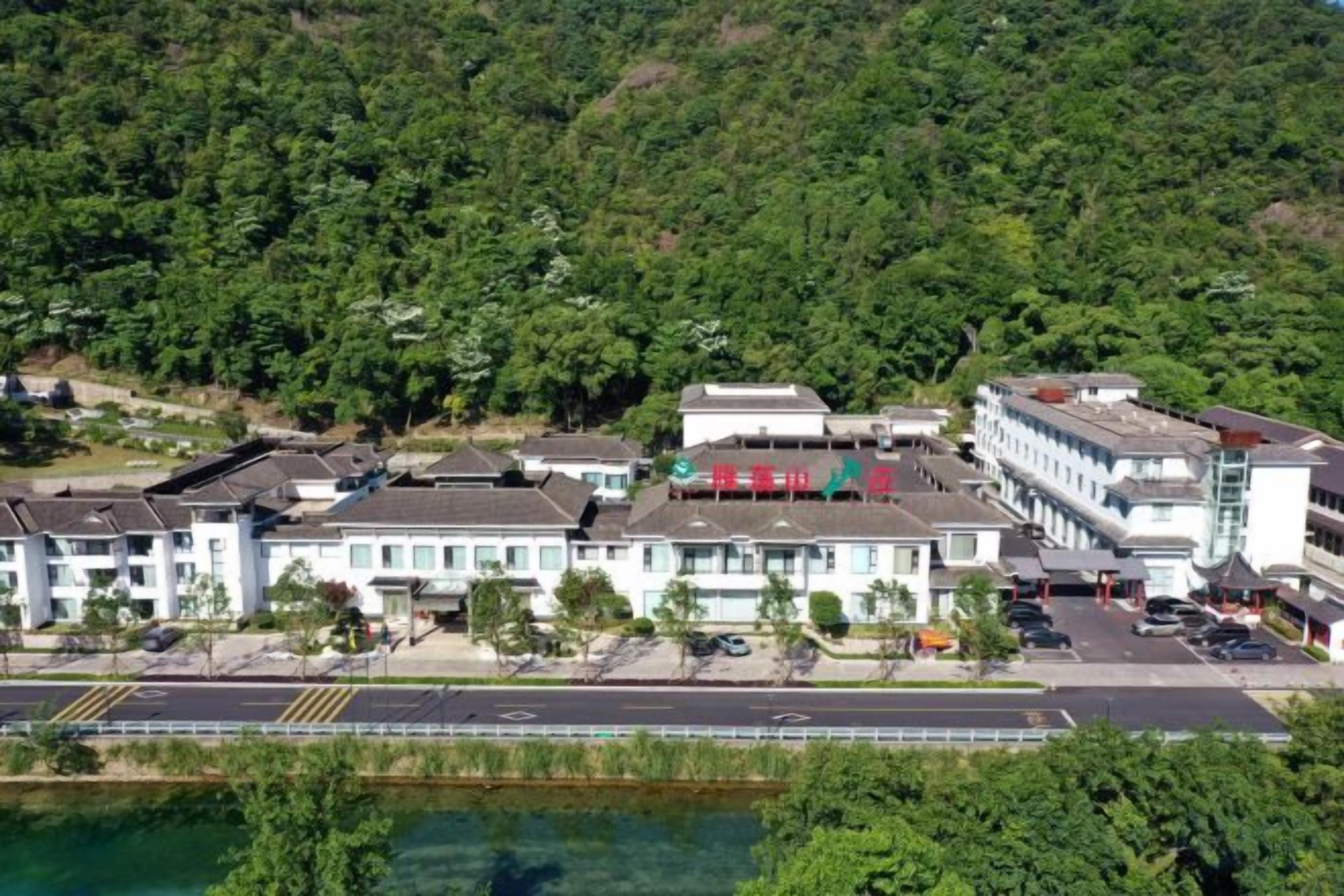 A multi-story hotel with a parking lot and a river in the foreground.