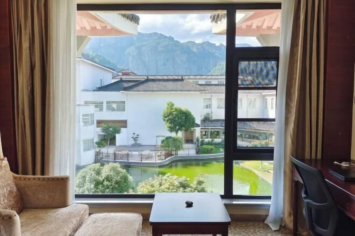 A room with a view of traditional buildings, a small table, a chair, and a desk.